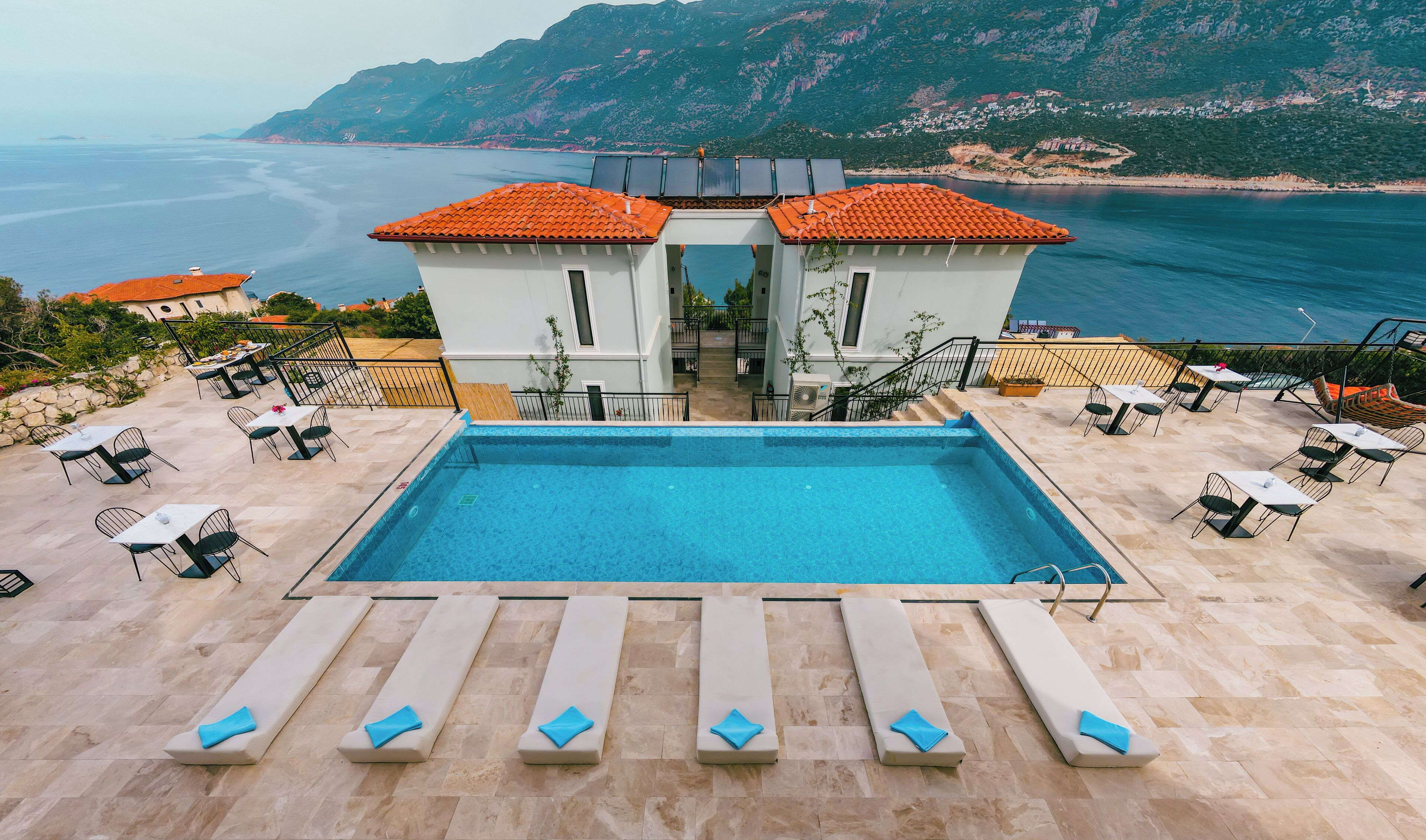 A pool area with lounge chairs and a view of the sea.