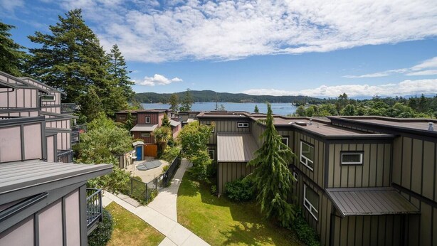 A residential area with modern houses, a clear view of a lake, and a well-maintained lawn. - 2 Bedroom Sooke Townhome (Sooke)