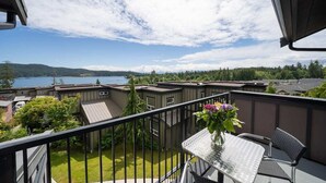 Ein Balkon mit Tisch und Stühlen mit Blick auf einen See und Wohnhäuser.