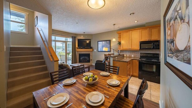 A spacious kitchen with wooden cabinets, a built-in microwave, and a large dining table set for four.