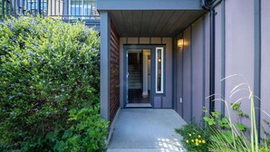 A modern building entrance with a concrete pathway, a metal gate, and a staircase leading inside. - Sooke Townhome, 3 Bedrooms (Sooke)
