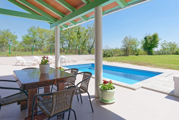 A covered outdoor area with a pool, a table with chairs, and potted plants. - Holiday Home Gimino - Two Bedroom Holiday Home with Pool (Zminj)