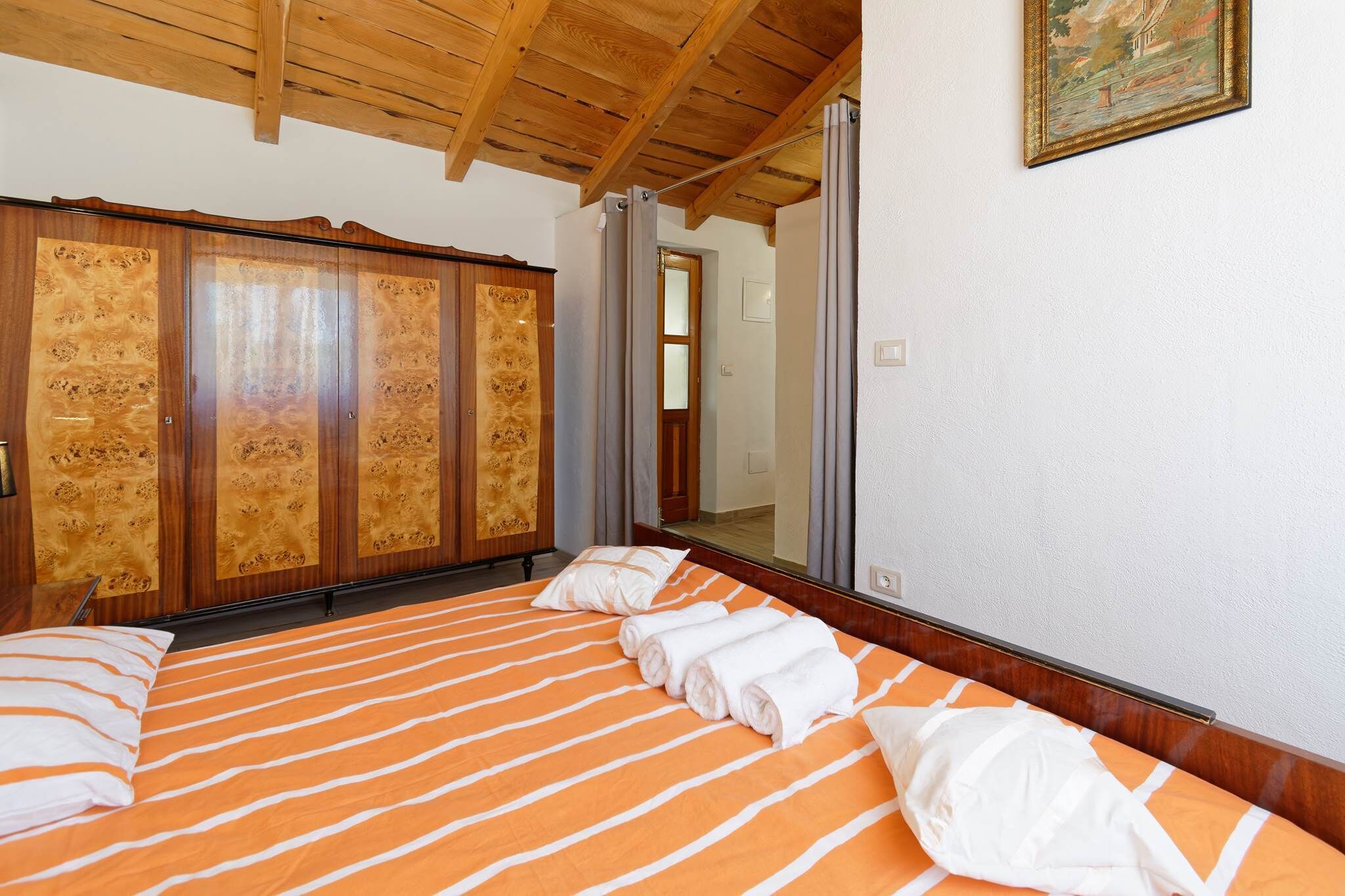 A bedroom with a large bed, wooden wardrobe, and a mirror.
