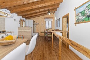 Una cucina rustica con travi in legno, un'area pranzo con tavolo e sedie in legno, e un quadro appeso al muro.
