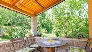 An outdoor patio with a round table, two cushioned benches, and a yellow vase. - Casa Mira - Two Bedroom Holiday Home with Pool (Pazin)