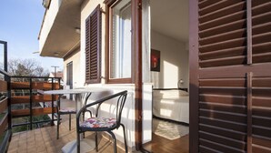 A patio with a table and chairs, a wooden fence, and a building with a window and shutter. - Apartment Nola - Two Bedroom Apartment with Balcony (Porec)