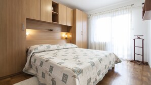 A bedroom with a bed, wooden wardrobe, and a bedside table. - Apartment Nola - Two Bedroom Apartment with Balcony (Porec)