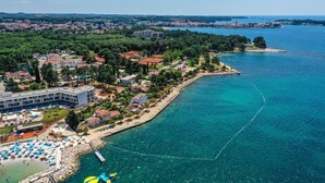 An aerial view of a coastal area with a hotel, beach, and clear blue sea. - Apartment Nola - Two Bedroom Apartment with Balcony (Porec)