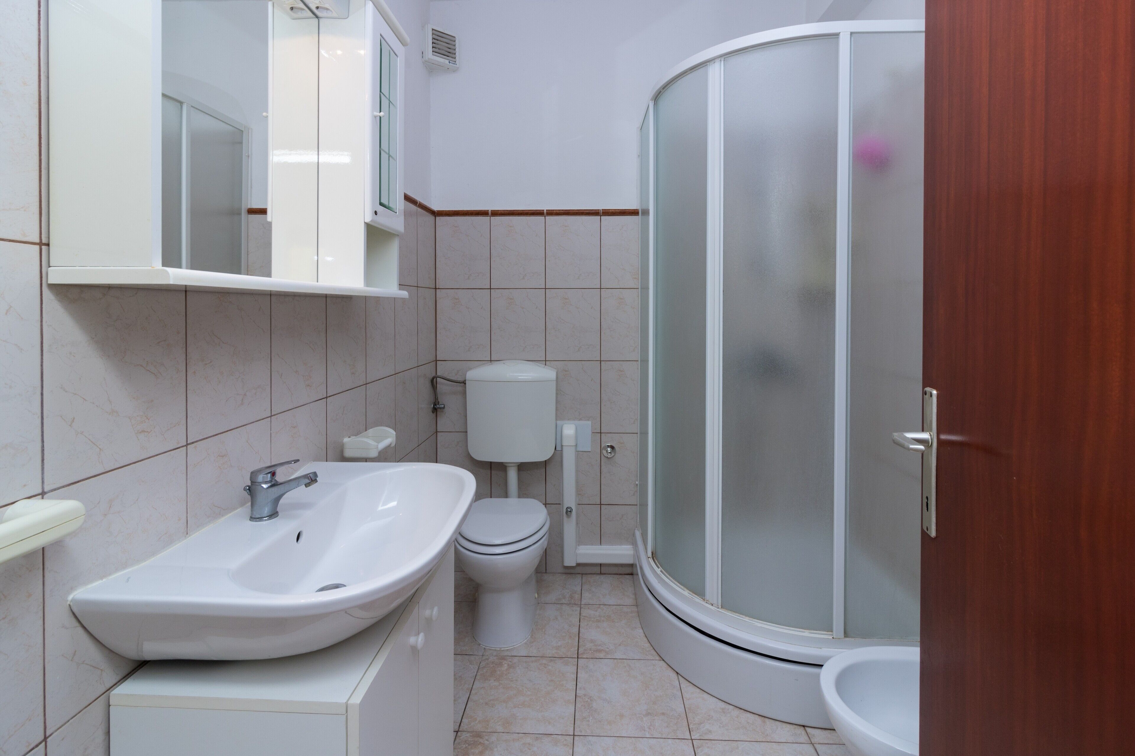 Une salle de bain équipée d’un lavabo, de toilettes et d’une douche à parois de verre.