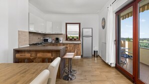 A modern kitchen with a wooden island, bar stools, a refrigerator, and a view of the outdoors. - Apartments Belvedere-Three Bedroom Apartment with Balcony (Buje)