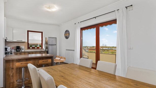 A modern kitchen with a wooden countertop, white cabinets, and a view through a sliding glass door to an outdoor balcony. - Apartments Belvedere-Three Bedroom Apartment with Balcony (Buje)