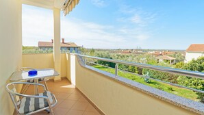 A balcony with a metal table and chair, a blue bowl, and a view of houses and greenery. - Apartments Belvedere-Three Bedroom Apartment with Balcony (Buje)