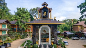 A building with a central entrance, surrounded by well-maintained gardens and parked cars. - Phumontra Resort Nakhon Nayok (Nakhon Nayok)