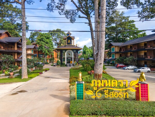 A hotel entrance with a central building, surrounded by lush greenery and multiple guest rooms. - Phumontra Resort Nakhon Nayok (Nakhon Nayok)