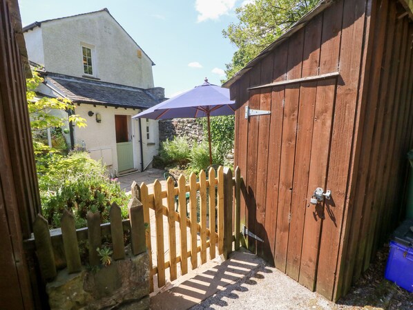 A wooden gate with a metal latch, a stone wall, and a wooden fence.