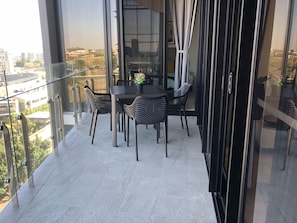 Enjoy the city view from this balcony with a table, chairs, and a potted plant.