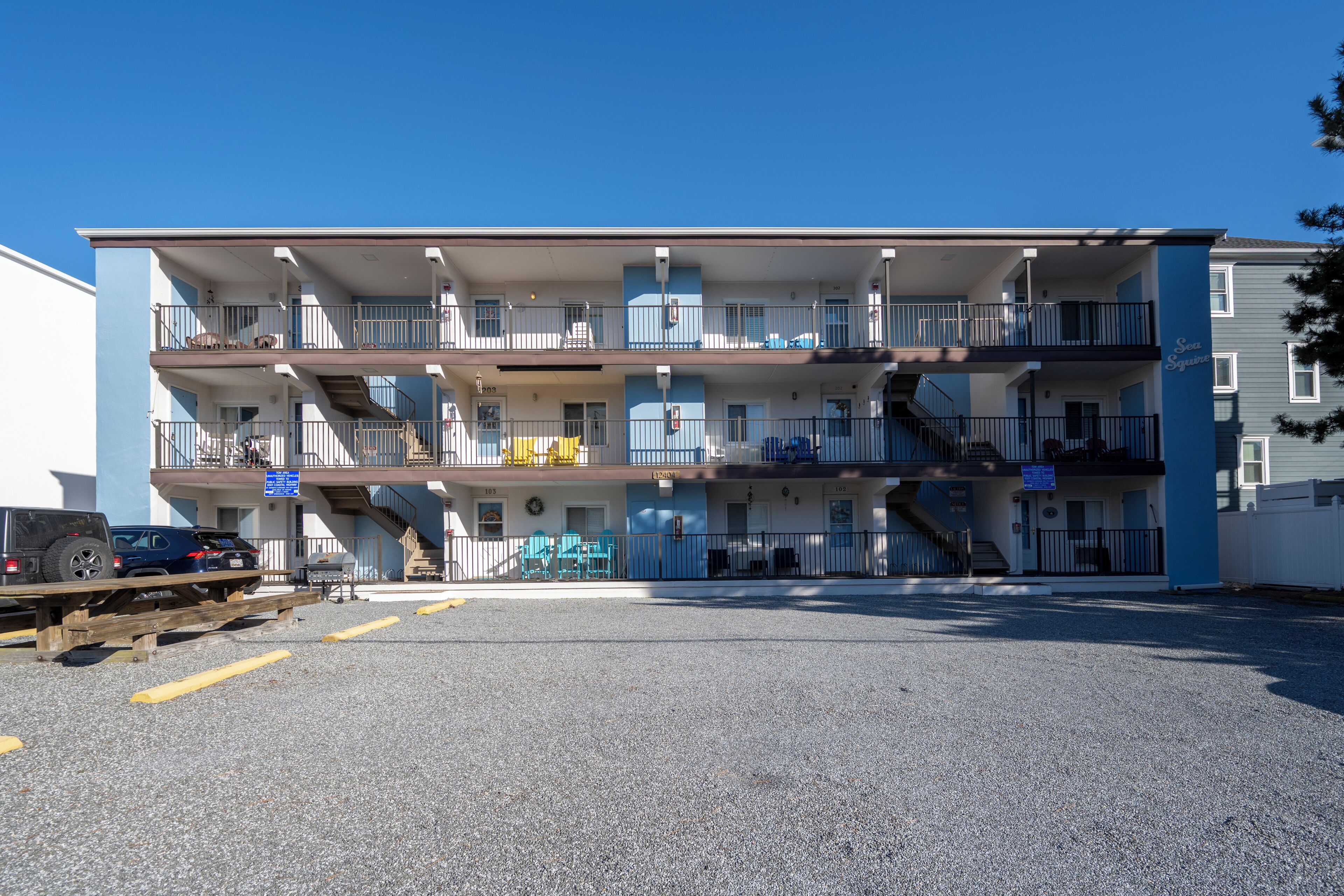 Een motel met meerdere verdiepingen, balkons, een parkeerplaats en een zichtbare trap.