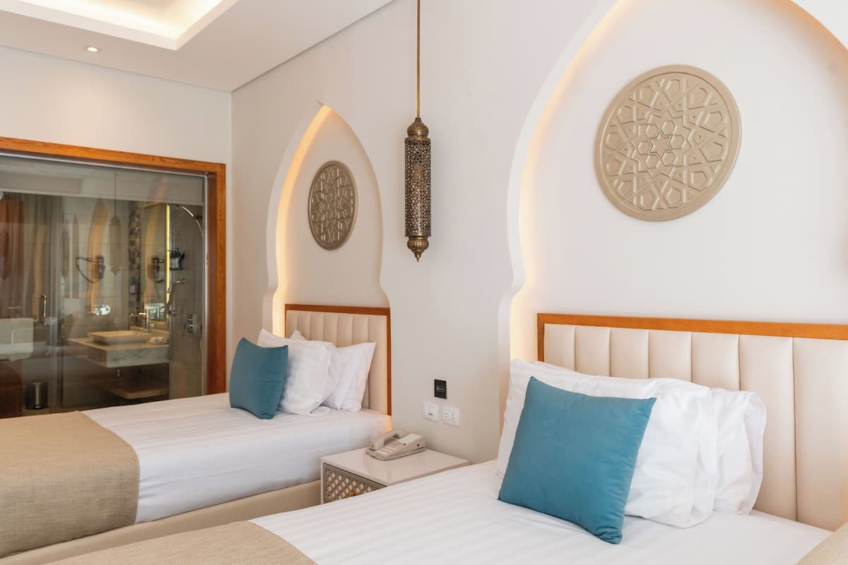 Ein Hotelzimmer mit zwei Betten, einem Nachttisch mit Telefon und Wanddekoration.