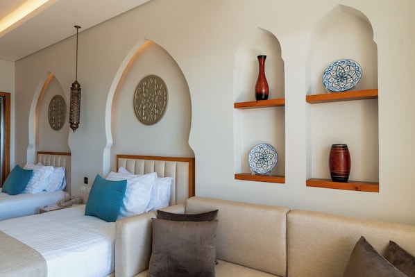 A hotel room with two beds, a sofa, decorative wall shelves, and a hanging light fixture. - SUNRISE Remal Beach Resort (Sharm El Sheikh)