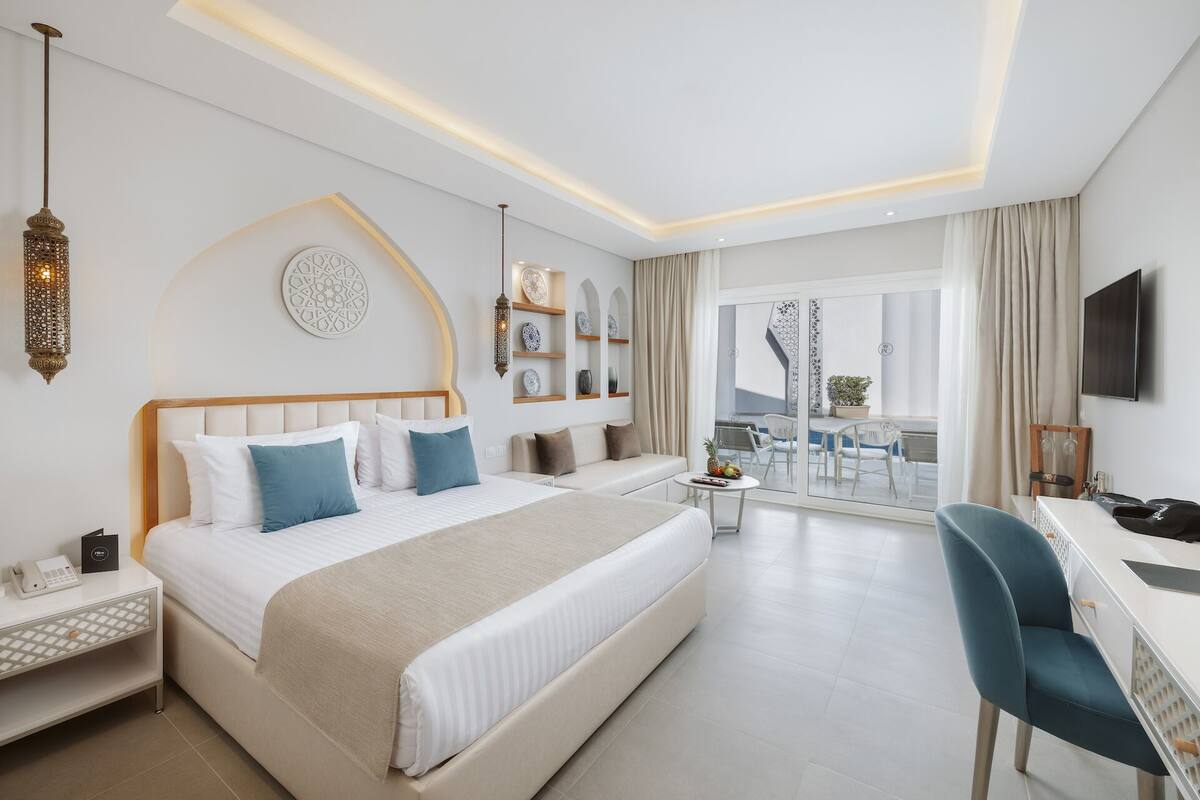 Ein modernes Hotelzimmer mit einem großen Bett, Nachttischen, einem Schreibtisch und einem Balkon mit Aussicht.