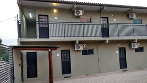 Un bâtiment à deux étages doté de plusieurs unités de climatisation, d’une entrée sécurisée par un portail et d’une allée gravillonnée.