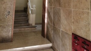 A staircase with a handrail, a light fixture above, and a red storage unit. - Oriente DNA Studios V (Loures)
