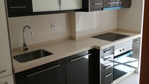 A modern kitchen with black and white cabinetry, a stainless steel sink, and a built-in oven. - Oriente DNA Studios V (Loures)
