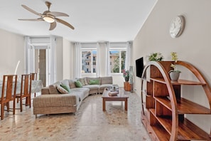 A living room with a sofa, coffee table, TV, and a wooden shelf unit. - Riva Dante Apartments (Riva del Garda)