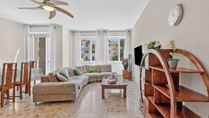 Un salon comprenant un canapé, une table basse, un téléviseur et une étagère en bois.