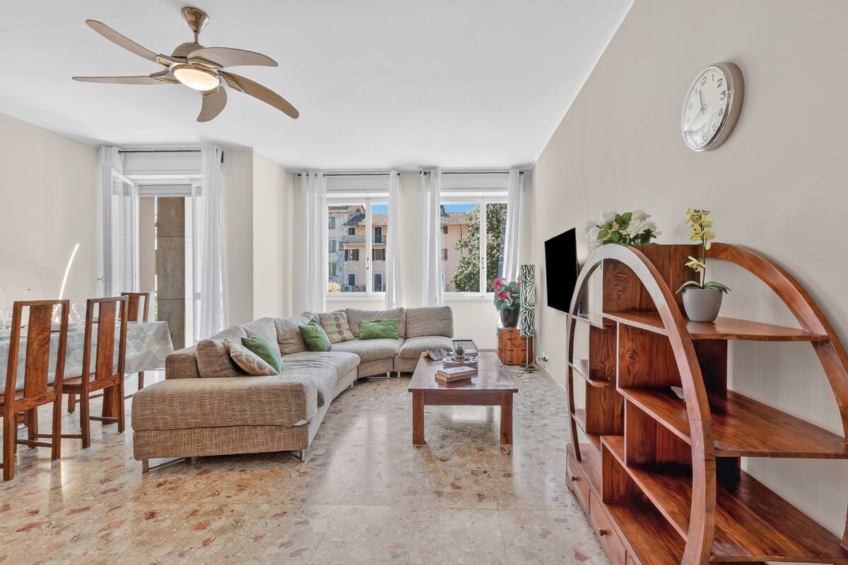 A living room with a sofa, coffee table, TV, and a wooden shelf unit.