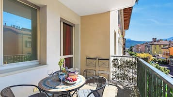 Un balcon avec une table dressée pour deux personnes, une chaise, une fenêtre et une vue sur le paysage urbain.