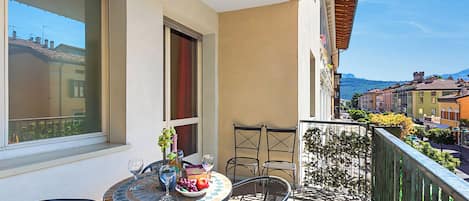 A balcony with a table set for two, a chair, a window, and a view of the cityscape.
