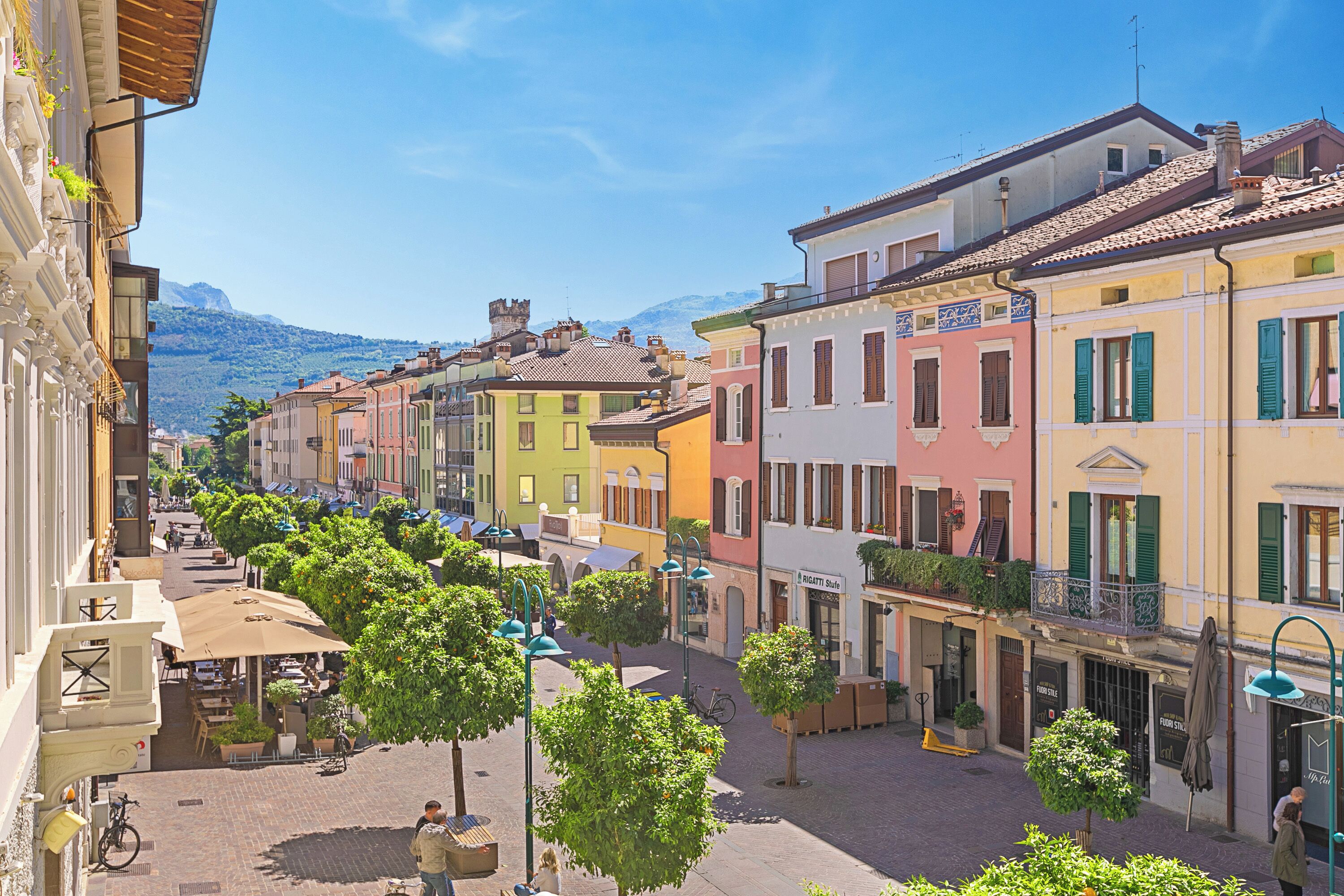 Eine Straße mit bunten Häusern, Bäumen und einem Berg im Hintergrund.