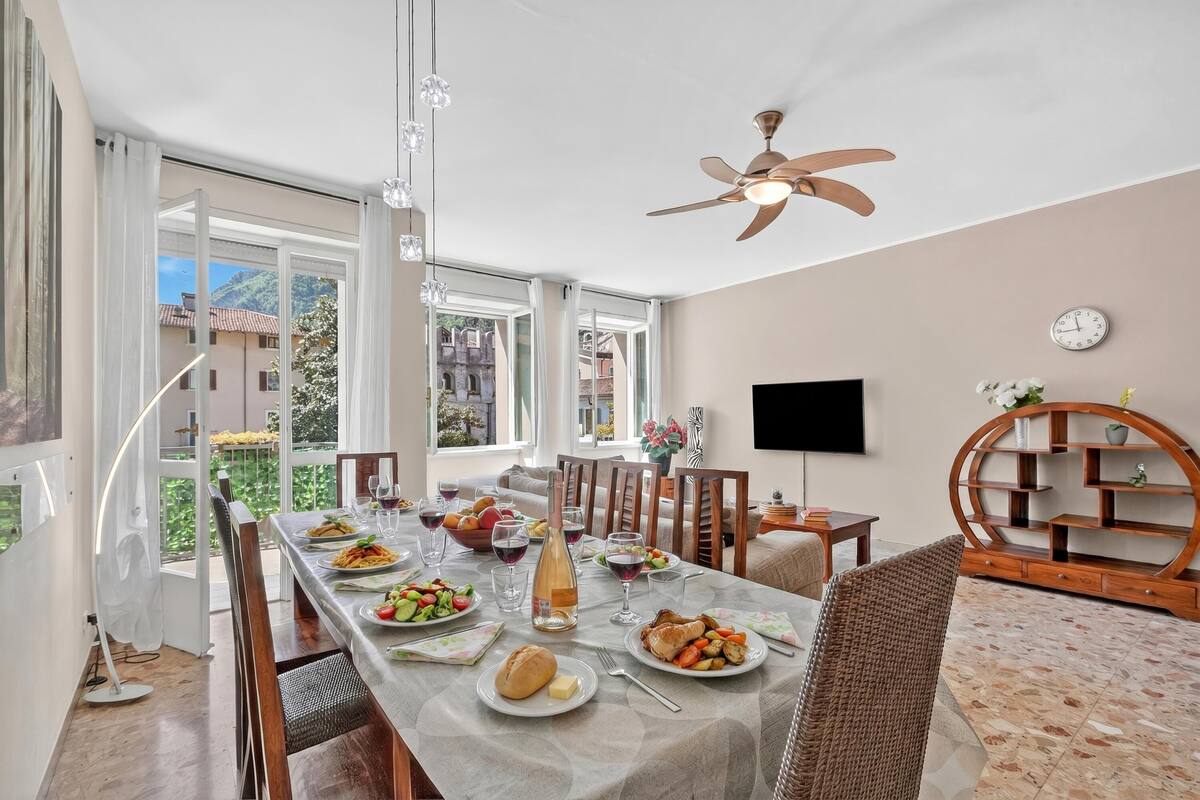 A dining area with a table set for a meal, a ceiling fan, and a view of the outside.