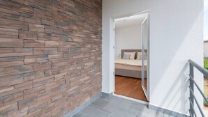 Une chambre moderne avec un mur en pierre, un plancher en bois et un lit recouvert de linge de lit blanc.