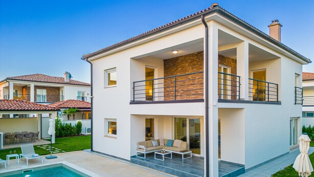 Une maison moderne à deux étages, dotée d’une piscine, d’un espace extérieur aménagé et d’un jardin bien entretenu.