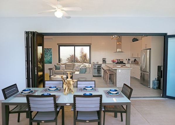 A modern kitchen with a built-in oven, a refrigerator, and a dining area with a table set for four.
