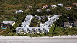Vista aérea de un resort costero con varios edificios, una playa y un campo de golf.