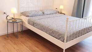 A single bed with a metal frame, two bedside tables with lamps, and a wooden floor. - Superior Beach Apartments Marina di Ragusa (Marina di Ragusa)