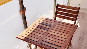 A wooden table and chairs set on a balcony with a view of the sky. - Superior Beach Apartments Marina di Ragusa (Marina di Ragusa)