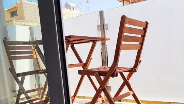 A room with a sliding glass door leading to an outdoor balcony with wooden chairs and a table. - Superior Beach Apartments Marina di Ragusa (Marina di Ragusa)