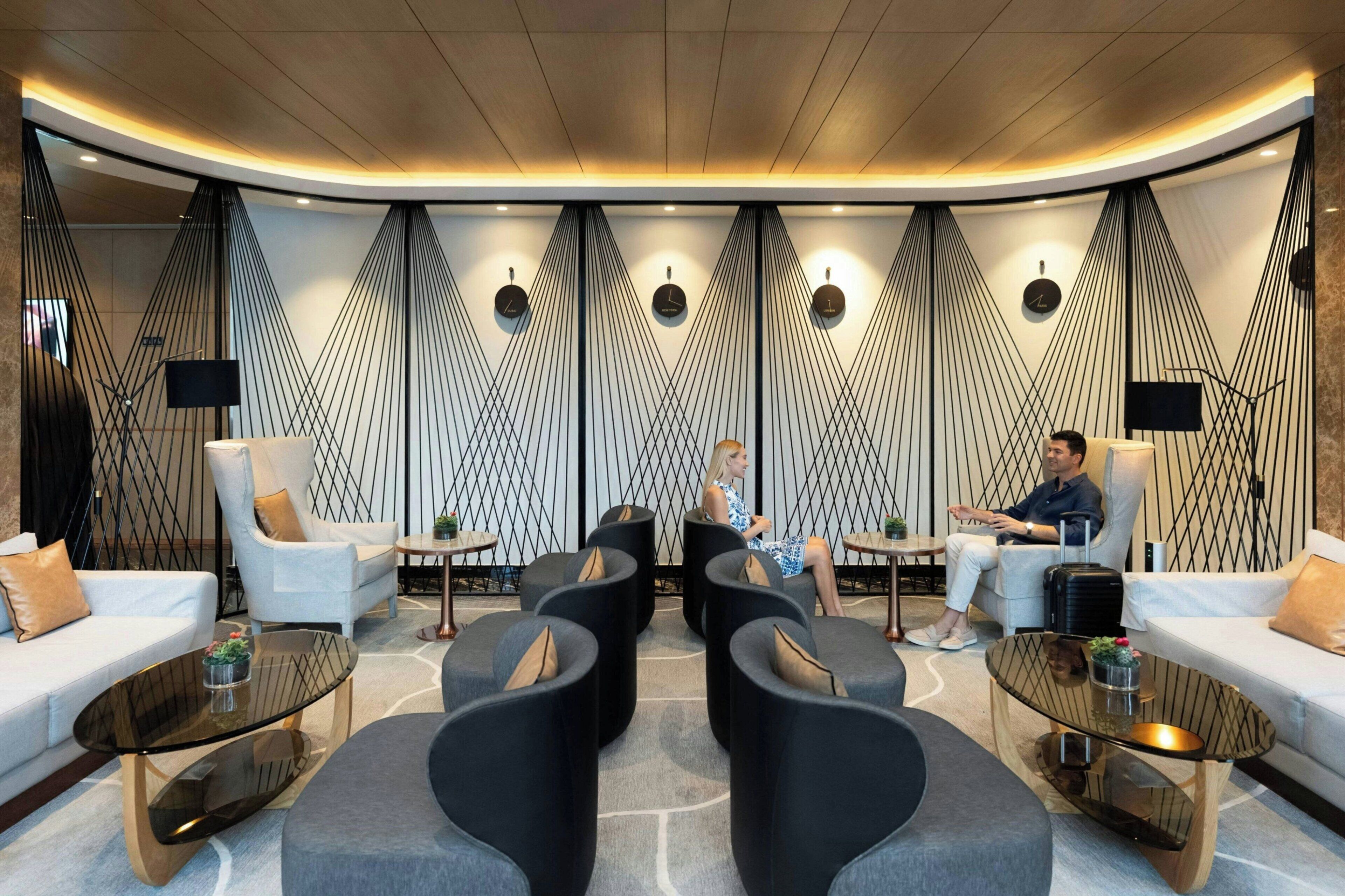 A modern lounge area with seating, tables, and a unique geometric wall design.
