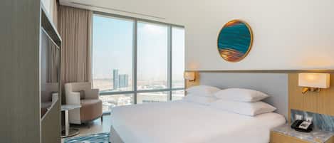 A hotel room with a large bed, a desk, a chair, and a view of the city.