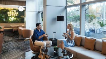 A modern lounge area with a glass coffee table, a sofa, and a seating area with a view of the outdoors.