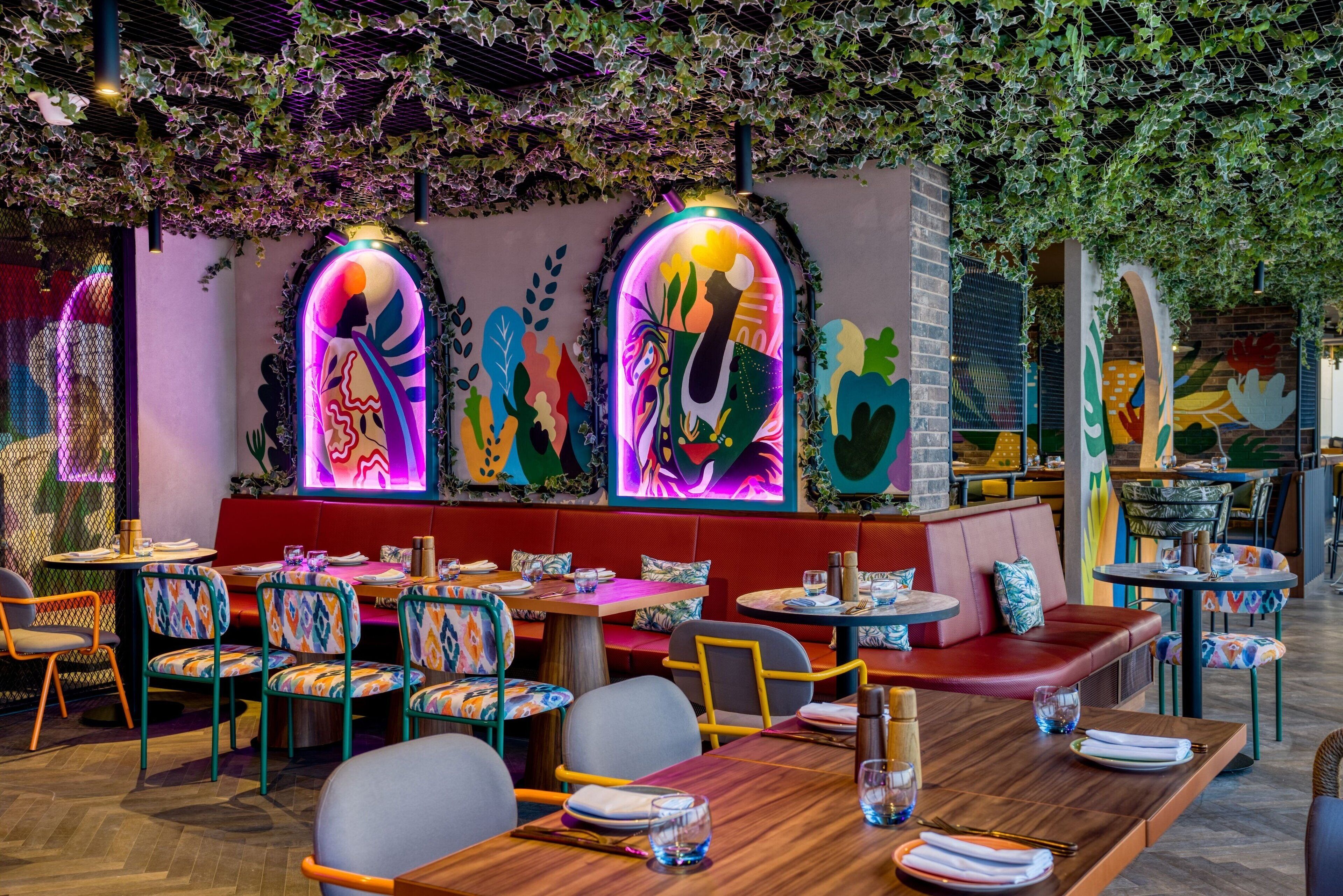 A restaurant with colorful murals, wooden tables, and cushioned seating.