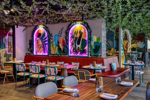 A restaurant with colorful murals, wooden tables, and cushioned seating.
