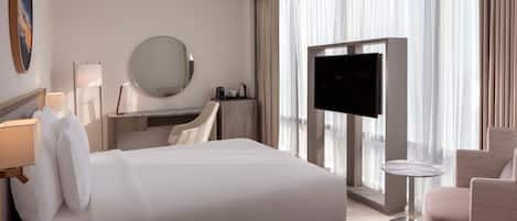 Quarto de hotel com uma cama grande, televisão, escrivaninha e uma cadeira.
