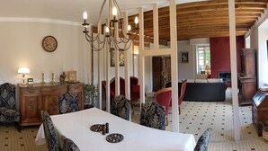 Een eetgedeelte met een witte tafel, gestreepte stoelen, een houten kast en een kroonluchter.
