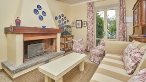 A living room with a fireplace, a sofa, a coffee table, and a bookshelf. - Marciana Hills Apartments (Marciana)