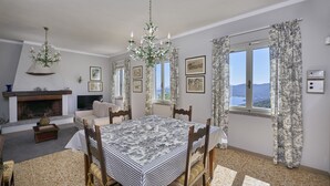 A dining area with a table set for four, a fireplace, and a view of the mountains through the window. - Marciana Hills Apartments (Marciana)